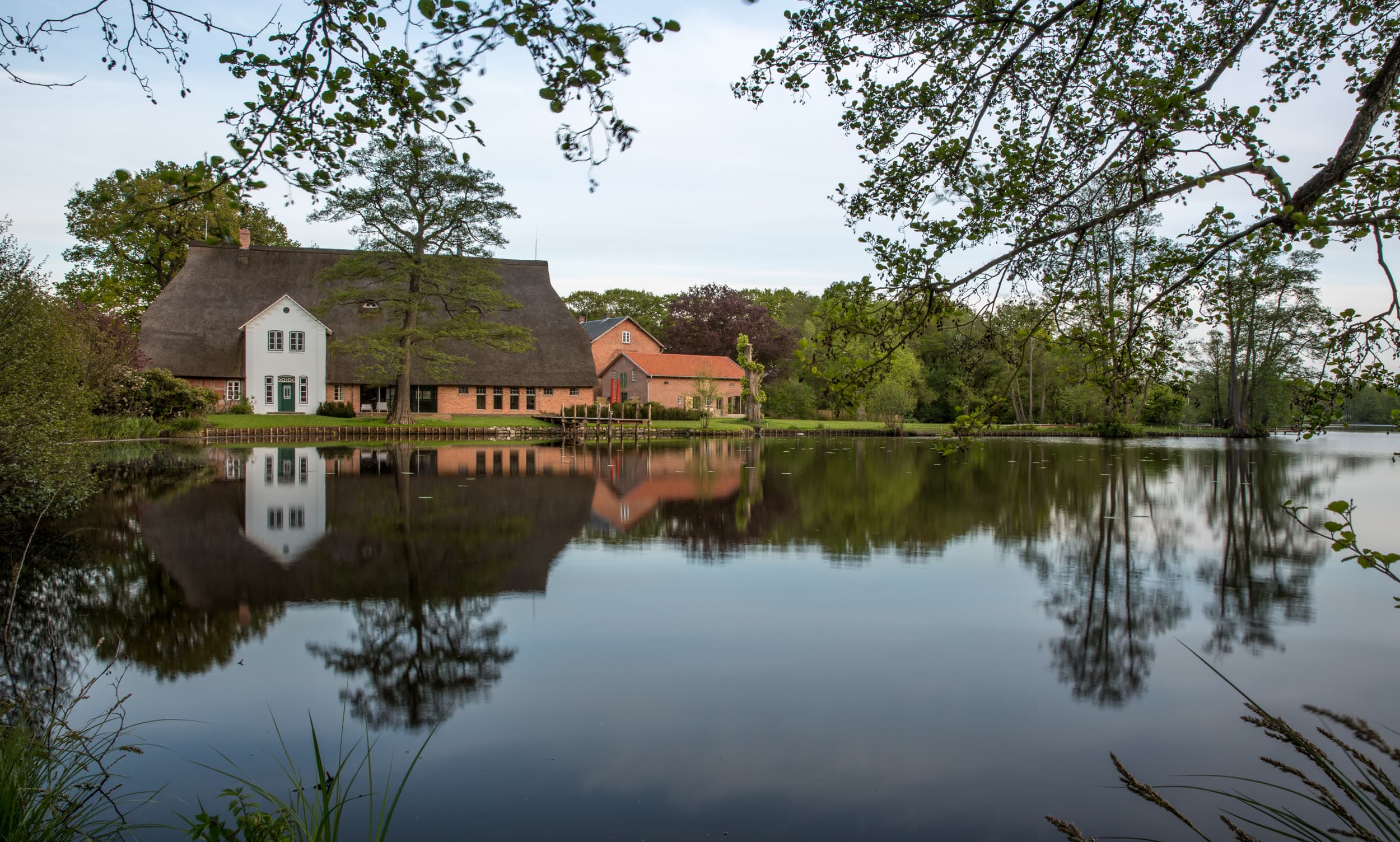 Reetdachhaus mit Spiegelung im Mühlenteich