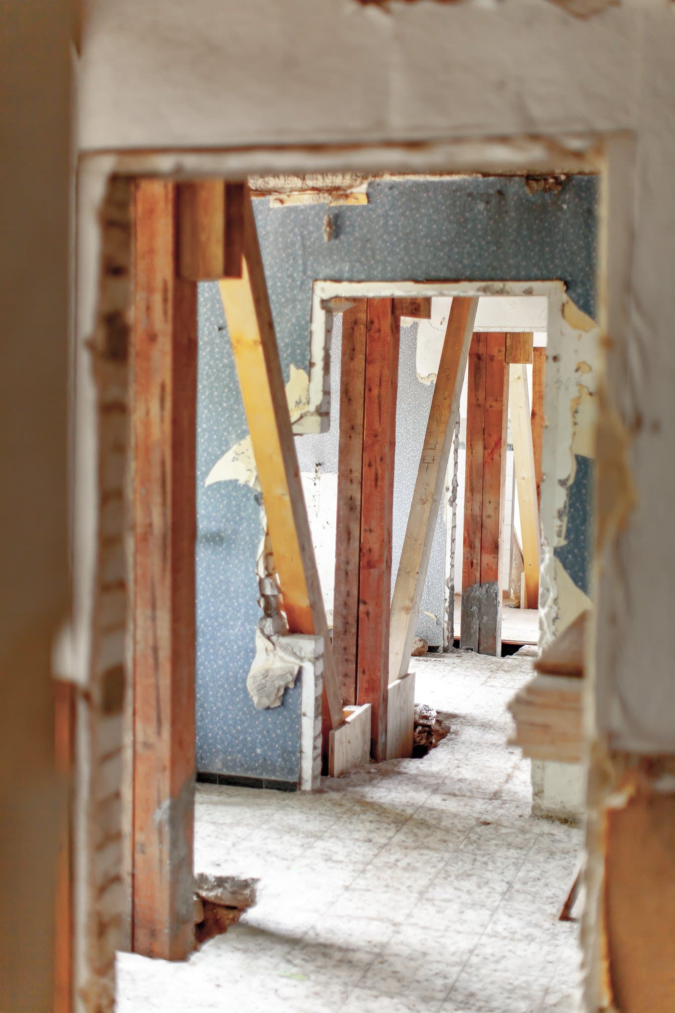 Entkernte Räume mit freigelegten Holzstützen und alter Tapete während der Sanierung