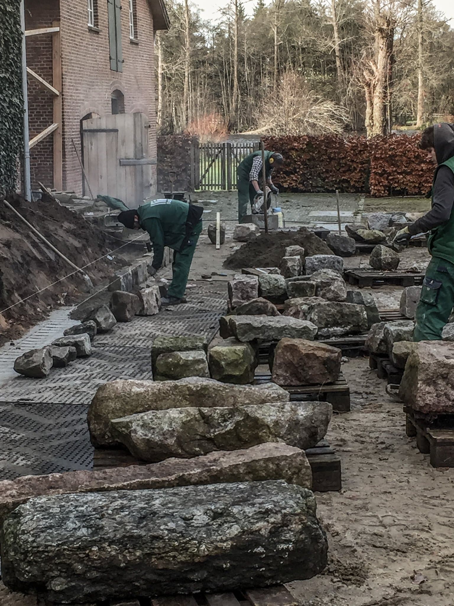 Mitarbeiter verlegen Natursteine und Findlinge im Hof
